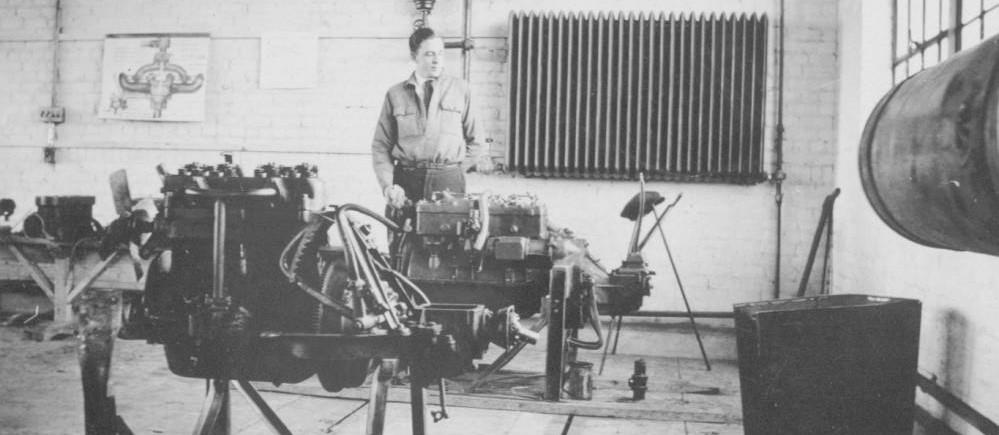 Man stands next to a machine in the mechanics classroom