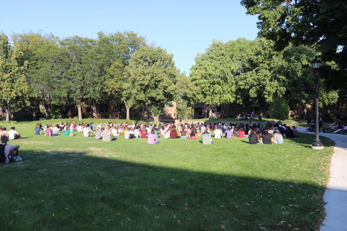A group of students sits outside on the Campus Mall in the grass.