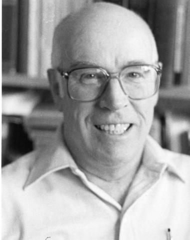 Black and white photograph headshot of William Donald Spring. He's wearing a button down shirt and glasses. 